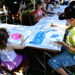 Kinder sitzen an einem großen Tisch und malen