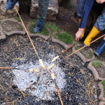 Kinder grillen Stockbrot auf einer Feuerstelle