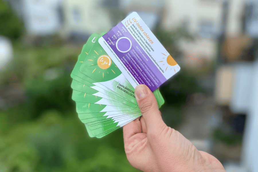 Eine Hand hält UV-Indexkarten
