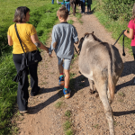 Eine Frau mit zwei Kindern wandert mit einem Esel