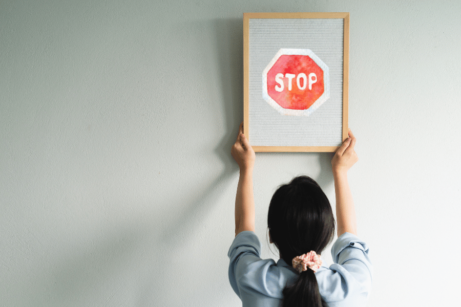 Eine Frau hängt einen Bilderrahmen mit einem Stoppschild darin auf.