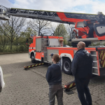 Ein Feuerwehrfahrzeug und mehrere Menschen, die es betrachten.