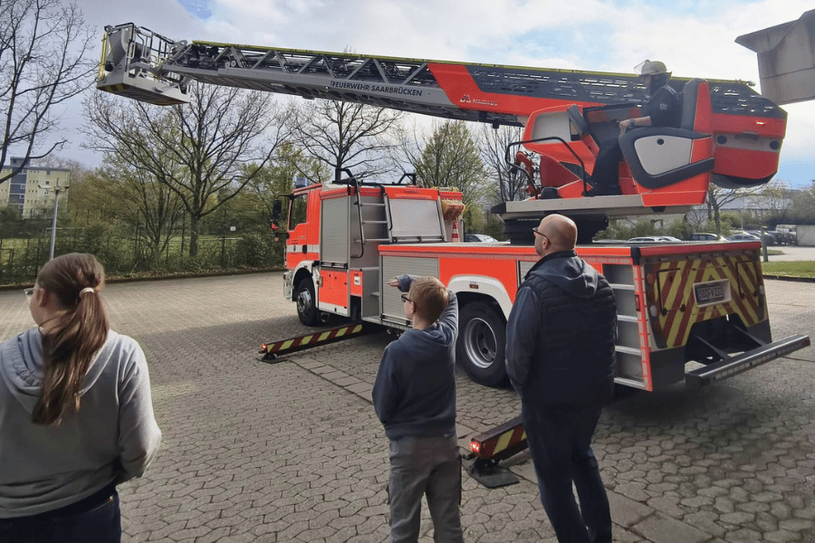 Ein Feuerwehrfahrzeug und mehrere Menschen, die es betrachten.
