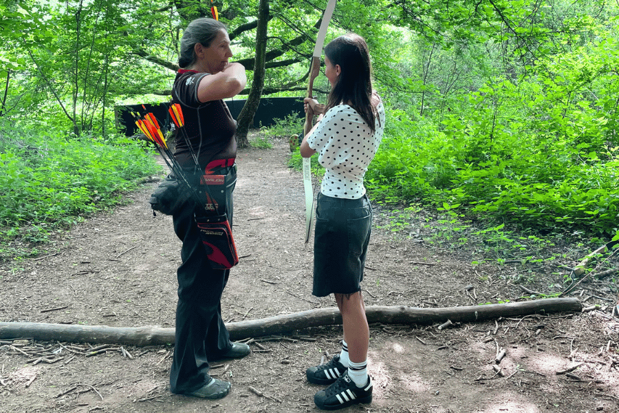 Zwei Personen im Wald beim Bogenschießen
