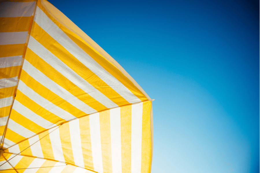 Ein gelb weißer Sonnenschirm vor blauem Himmel
