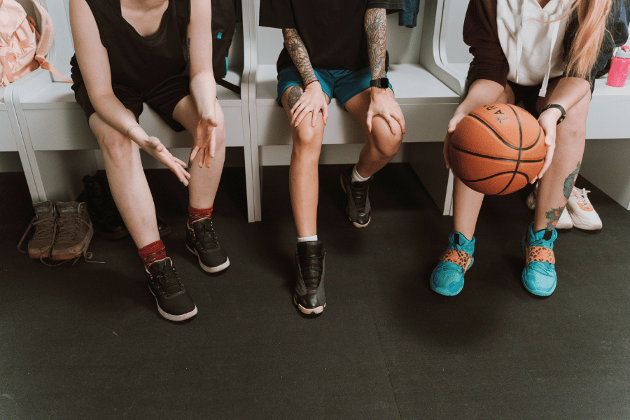 Drei Frauen in einer Sportkabine, eine hält einen Basketball